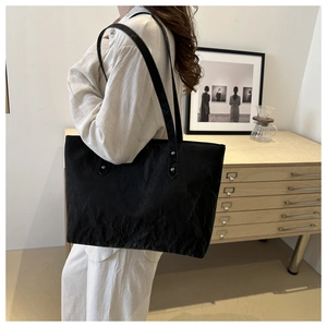 Gros plan sur le sac cabas noir en tissu texturé avec fines anses et rivets