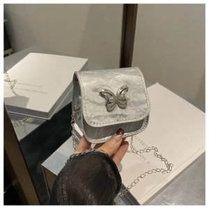 Detail of silver metallic pleated mini bag featuring a large decorative butterfly buckle