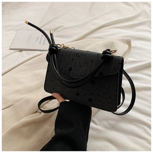 Detail of black star print crossbody bag with knotted handle and textured fabric