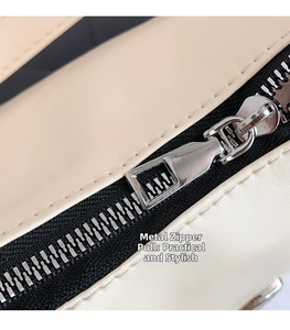 Dettaglio della cerniera in metallo argentato e cuciture precise su borsa in pelle beige