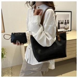 Dettaglio della borsa tote nera con finiture in pelle marrone e piccola pochette