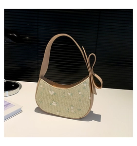 Detailed embroidery of white flowers on a green woven crescent bag with leather bow