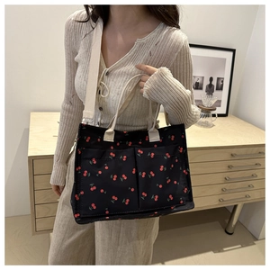 Detail view of canvas tote bag with cherry print and adjustable strap on a model