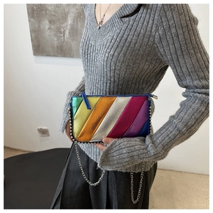 Rainbow stripe crossbody bag with metallic finish and chain strap worn over grey sweater