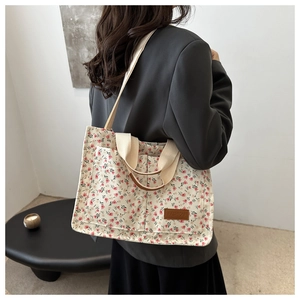 Detailed shot of floral canvas tote bag featuring double front pockets and leather logo