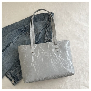 Détail du cabas argenté avec texture plissée et accents de rivets métalliques