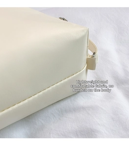Dettaglio delle cuciture precise e della texture in ecopelle bianco crema della borsa