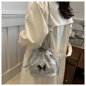 Sac seau argenté avec papillon en métal et texture plissée porté en bandoulière