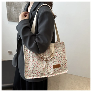 Close-up of floral canvas tote bag featuring double straps and leather fashion label