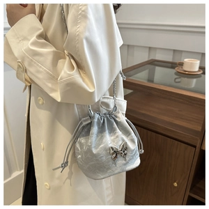 Détail du sac seau plissé argenté avec papillon métallique et bandoulière en chaîne