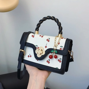 Chic cherry print handbag with golden flower clasp and black twisted handle shown in hand