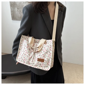 Detail of floral canvas tote bag featuring double front pockets and brown fashion label
