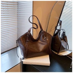 Détail d'un sac cabas rétro marron avec texture cuir huilé sur un bureau en bois