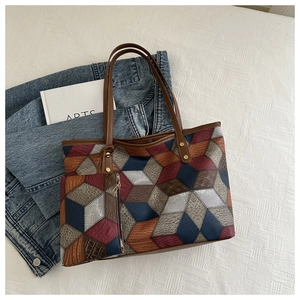 Dettaglio borsa tote con motivo geometrico, trama in pelle e piccola pochette abbinata