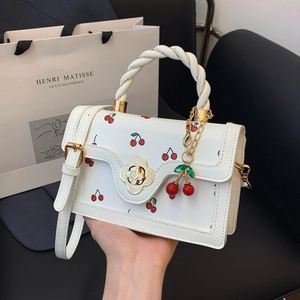 White cherry print handbag with metal floral clasp and 3D cherry charm accessory