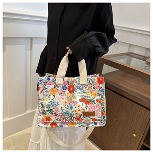 Detailed shot of floral canvas tote bag with brown leather label and adjustable shoulder strap