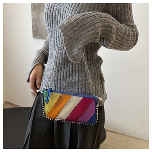 Detail of colorful striped crossbody bag with silver rivet studs and metal chain strap