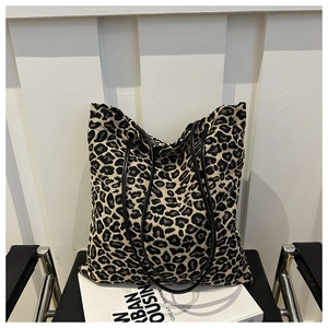 Close-up of leopard print tote bag with black leather straps and gold metal ring details
