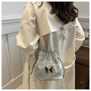 Sac seau argenté avec texture froissée et papillon en métal liquide sur un mannequin