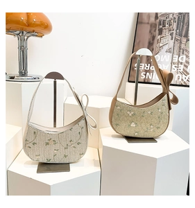 Detailed view of crescent straw shoulder bags with floral embroidery and bow accents