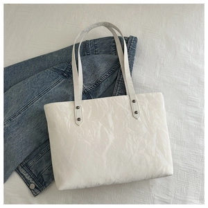 Vue détaillée du sac cabas blanc avec texture froissée et détails de rivets foncés
