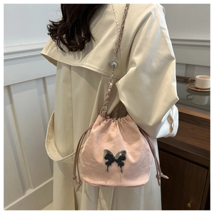 Détail du sac seau rose à cordon avec papillon en métal argenté et bandoulière chaîne