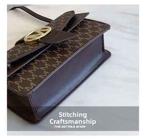 Macro detail of brown leather bag with M pattern print and gold metal logo buckle