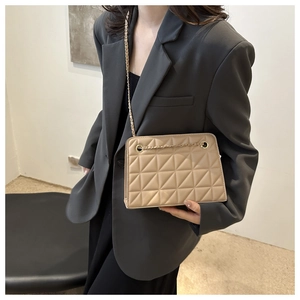 Chic beige quilted crossbody bag with gold chain strap on a professional model