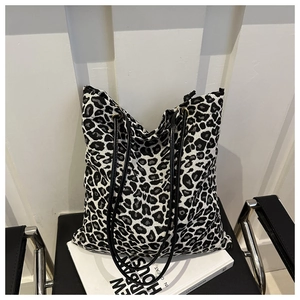 Detailed view of the leopard print tote bag with black faux leather straps and canvas texture
