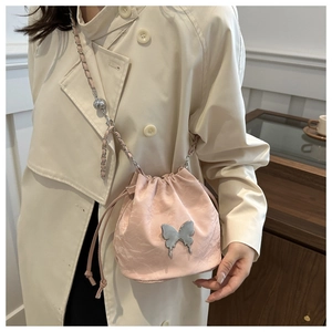 Sac seau rose avec cordon de serrage, ornement papillon argenté et bandoulière chaîne