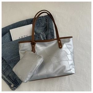Dettaglio della borsa tote argento metallizzato con cuciture geometriche e pochette coordinata