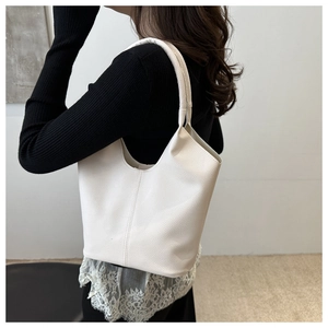 Close-up of cream white lychee texture leather bucket bag worn as a shoulder bag