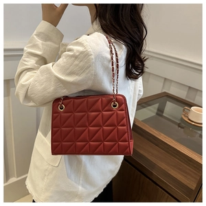 Red quilted shoulder bag with gold chain strap shown on model for size and style