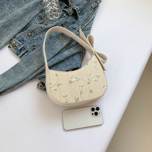 Beige floral lace underarm bag with embroidery and large bow strap detail on denim