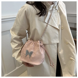 Détail du sac seau en satin rose avec papillon métallique et bandoulière en chaîne