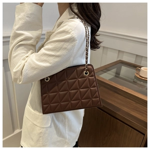 Detail of dark brown quilted crossbody bag with sliding gold metal chain strap