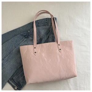 Détail d'un cabas rose avec texture plissée et rivets métalliques sur les bandoulières