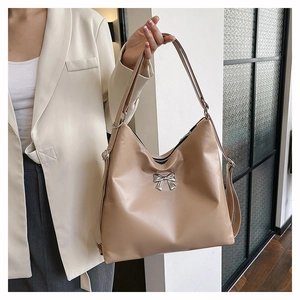 Dettaglio del fiocco argentato su una grande borsa tote beige in ecopelle con zip