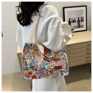 Detail of floral canvas tote bag showing the patterned fabric and durable strap on model