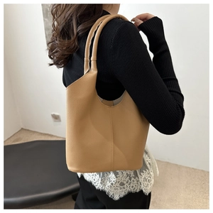 Close-up of the camel textured leather tote bag worn on shoulder by a model