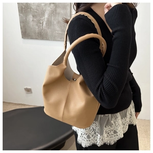 Close-up of camel litchi grain leather bucket bag featuring a soft integrated handle