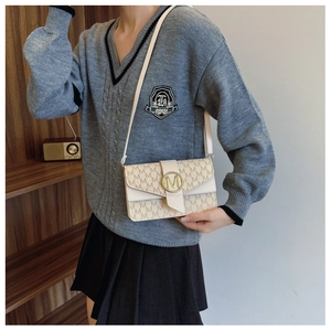 Detail of monogram M print shoulder bag with gold metal hardware on model's outfit