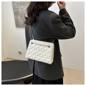 Detail of white quilted geometric shoulder bag with light gold chain strap on model