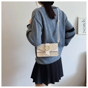Detailed view of cream PU leather shoulder bag with gold M-logo clasp and pattern