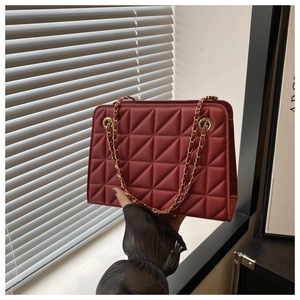 Detailed macro of burgundy quilted shoulder bag with elegant gold chain strap