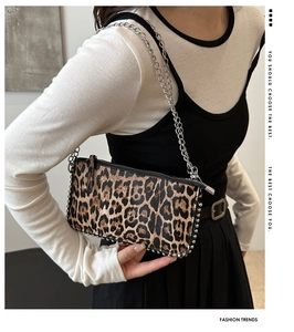 Detail view of leopard print crossbody bag featuring silver metal chain and side rivets