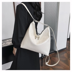 Dettaglio di una borsa tote bianco crema con un fiocco decorativo in metallo argento