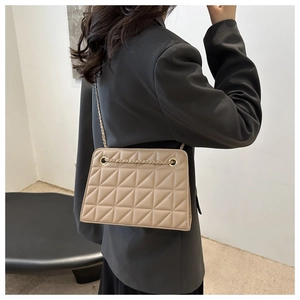 Detail of beige quilted square bag with gold chain strap on model for 2024 fashion