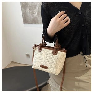 Détail du sac cabas en paille tissée avec poignées en cuir marron et bandoulière assortie