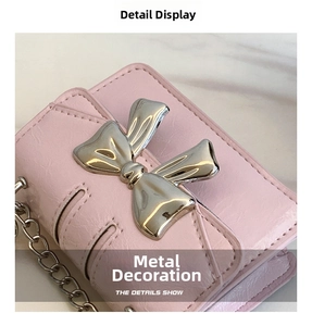 Close-up of pink leather mini bag featuring silver metal bow detail and chain strap